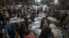 Foto konferensi pers yang beredar memperlihatkan para anggota staf medis berdiri di antara jasad-jasad yang ditutupi. (Foto Istimewa)