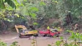 Excavator terlihat sibuk menggali dan mengangkut material ke dalam dump truck di lokasi tambang ilegal Bone