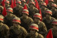 Pasukan militer Iran berbaris dengan membawa bendera merah dalam formasi siaga tempur.