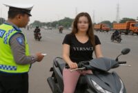 Foto ilustrasi – Oknum Polantas tilang seorang pengendara motor wanita di tengah jalan raya.