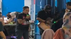 Udhin Leaders (kiri) saat ikut bernyanyi dengan seorang pengamen (kanan) yang menyanyikan lagu Salimu Naraka