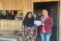 Mahasiswa KKN Unhas 114, Nur Asma-ul Husna Zahrah Firdaus, menyerahkan buku saku panduan desain promosi dan pendaftaran Google Maps kepada salah satu pelaku UMKM di Desa Teteaji.