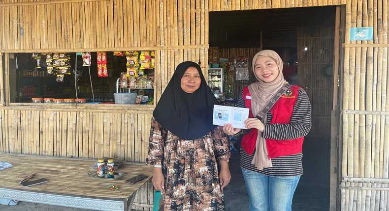 Mahasiswa KKN Unhas 114, Nur Asma-ul Husna Zahrah Firdaus, menyerahkan buku saku panduan desain promosi dan pendaftaran Google Maps kepada salah satu pelaku UMKM di Desa Teteaji.