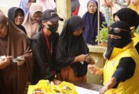 Ketua KPPG Luwu Timur, Sari M. Kamarong (berjilbab cadar dan mengenakan rompi kuning), melayani warga dalam kegiatan pasar murah yang digelar dalam rangka menyambut HUT Partai Golkar di Luwu Timur.