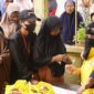 Ketua KPPG Luwu Timur, Sari M. Kamarong (berjilbab cadar dan mengenakan rompi kuning), melayani warga dalam kegiatan pasar murah yang digelar dalam rangka menyambut HUT Partai Golkar di Luwu Timur.