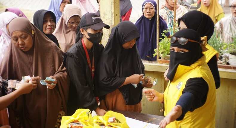 Ketua KPPG Luwu Timur, Sari M. Kamarong (berjilbab cadar dan mengenakan rompi kuning), melayani warga dalam kegiatan pasar murah yang digelar dalam rangka menyambut HUT Partai Golkar di Luwu Timur.