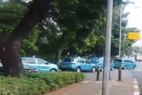 Sejumlah taksi Blue Bird terparkir di pinggir jalan dan menggunakan trotoar.