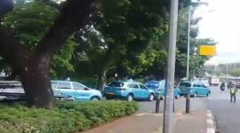 Sejumlah taksi Blue Bird terparkir di pinggir jalan dan menggunakan trotoar.