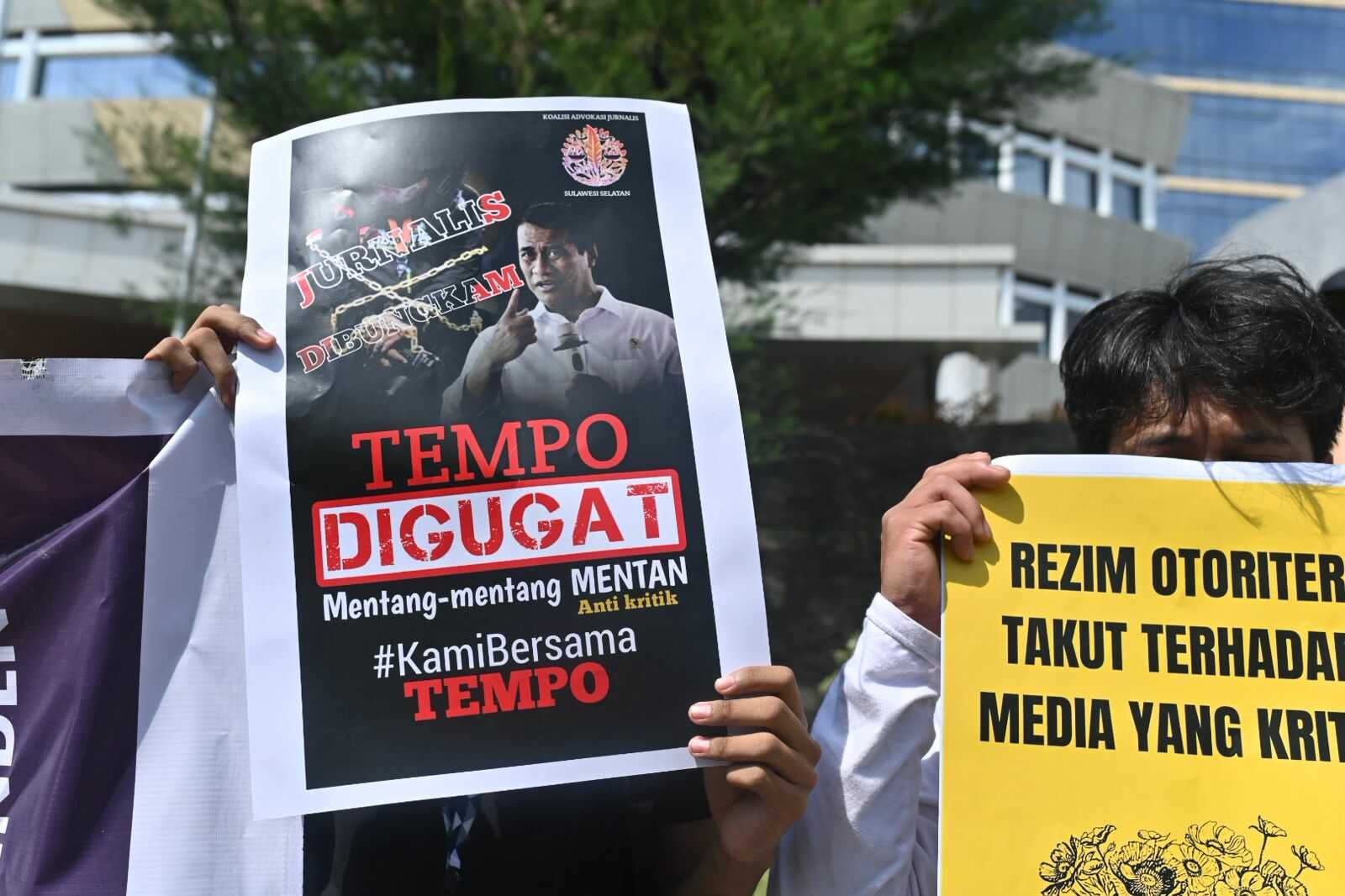 Demonstran memegang poster sebagai bagian dari aksi dukungan terhadap TEMPO. Poster yang berwarna hitam bertuliskan "Jurnalis Dibungkam, TEMPO Digugat, Mentang-mentang MENTAN Anti Kritik, #KamiBersamaTEMPO". Sementara poster yang berwarna kuning bertuliskan "Rezim Otoriter Takut Terhadap Media Yang Kritis”.