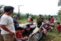 Warga Desa Rampoang berkumpul di tepi jalan sambil memantau aktivitas di sekitar lokasi proyek pembangunan Yon TP 872/Andi Jemma yang sementara dihentikan, Minggu (23/11/2025).