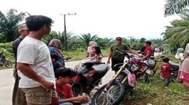 Warga Desa Rampoang berkumpul di tepi jalan sambil memantau aktivitas di sekitar lokasi proyek pembangunan Yon TP 872/Andi Jemma yang sementara dihentikan, Minggu (23/11/2025).