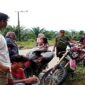 Warga Desa Rampoang berkumpul di tepi jalan sambil memantau aktivitas di sekitar lokasi proyek pembangunan Yon TP 872/Andi Jemma yang sementara dihentikan, Minggu (23/11/2025).