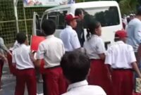Sejunlah siswa SD berkumpul di dekat mobil putih yang berhenti di area sekolah usai insiden