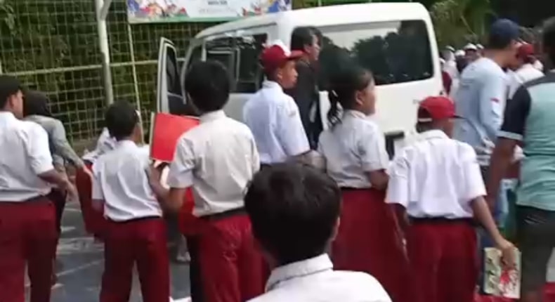 Sejunlah siswa SD berkumpul di dekat mobil putih yang berhenti di area sekolah usai insiden