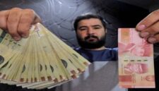 Seorang pria menunjukkan uang kertas Rp 100.000 (kanan) dan beberapa uang rial rial Iran (kiri). (Foto: Reuters)