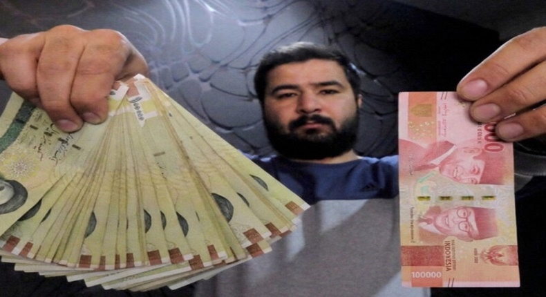 Seorang pria menunjukkan uang kertas Rp 100.000 (kanan) dan beberapa uang rial rial Iran (kiri). (Foto: Reuters)