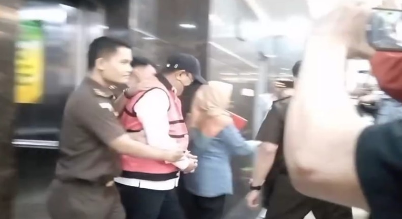 Mantan Pj Gubernur Sulsel, Bahtiar Baharuddin, digiring penyidik Kejati Sulsel mengenakan rompi tahanan merah dan topi usai ditetapkan sebagai tersangka kasus dugaan korupsi pengadaan bibit nanas.