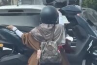 Tangkapan layar video viral yang memperlihatkan aksi seorang pengendara motor mengangkut motor lain di jalanan Kota Makassar. Polisi kini tengah menelusuri identitas pengendara dan wanita yang ada dalam video tersebut untuk diberikan sanksi tilang karena tindakannya membahayakan keselamatan.