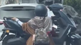 Tangkapan layar video viral yang memperlihatkan aksi seorang pengendara motor mengangkut motor lain di jalanan Kota Makassar. Polisi kini tengah menelusuri identitas pengendara dan wanita yang ada dalam video tersebut untuk diberikan sanksi tilang karena tindakannya membahayakan keselamatan.