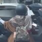 Tangkapan layar video viral yang memperlihatkan aksi seorang pengendara motor mengangkut motor lain di jalanan Kota Makassar. Polisi kini tengah menelusuri identitas pengendara dan wanita yang ada dalam video tersebut untuk diberikan sanksi tilang karena tindakannya membahayakan keselamatan.