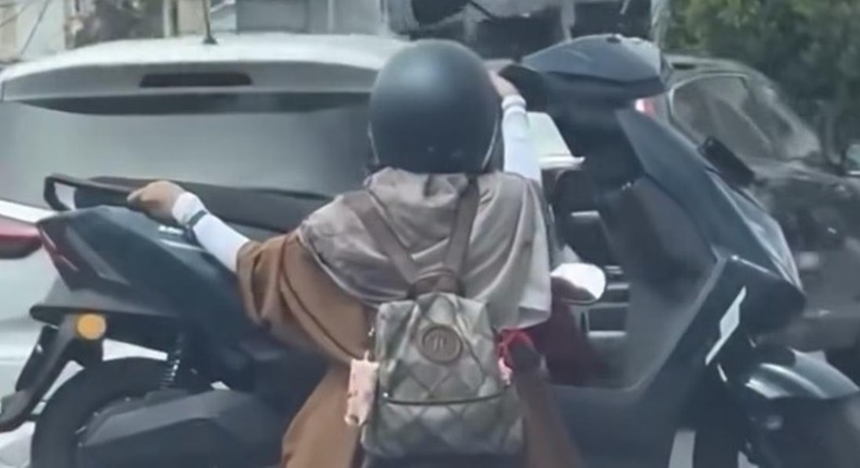 Tangkapan layar video viral yang memperlihatkan aksi seorang pengendara motor mengangkut motor lain di jalanan Kota Makassar. Polisi kini tengah menelusuri identitas pengendara dan wanita yang ada dalam video tersebut untuk diberikan sanksi tilang karena tindakannya membahayakan keselamatan.