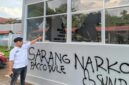 Petugas Lapas menunjuk kaca bangunan yang pecah serta coretan pilox di dinding pasca-aksi demonstrasi AMPH, Senin (25/5/2026). Coretan bertuliskan 