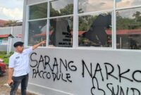 Petugas Lapas menunjuk kaca bangunan yang pecah serta coretan pilox di dinding pasca-aksi demonstrasi AMPH, Senin (25/5/2026). Coretan bertuliskan 