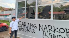 Petugas Lapas menunjuk kaca bangunan yang pecah serta coretan pilox di dinding pasca-aksi demonstrasi AMPH, Senin (25/5/2026). Coretan bertuliskan 