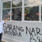 Petugas Lapas menunjuk kaca bangunan yang pecah serta coretan pilox di dinding pasca-aksi demonstrasi AMPH, Senin (25/5/2026). Coretan bertuliskan 