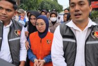 Mantan Bupati Gowa, Sitti Husniah Talenrang menggunakan rompi oranye dan kedua tangan diborgol tali tis usai keluar dari ruang penyidikan (Foto : Ist)