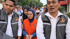 Mantan Bupati Gowa, Sitti Husniah Talenrang menggunakan rompi oranye dan kedua tangan diborgol tali tis usai keluar dari ruang penyidikan (Foto : Ist)