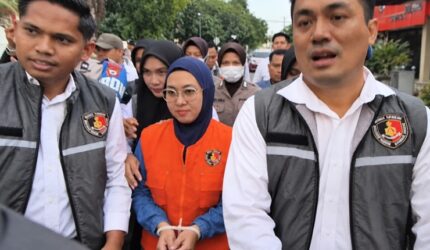 Mantan Bupati Gowa, Sitti Husniah Talenrang menggunakan rompi oranye dan kedua tangan diborgol tali tis usai keluar dari ruang penyidikan (Foto : Ist)