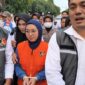 Mantan Bupati Gowa, Sitti Husniah Talenrang menggunakan rompi oranye dan kedua tangan diborgol tali tis usai keluar dari ruang penyidikan (Foto : Ist)