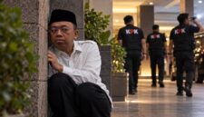 Ilustrasi dramatis Nusron Wahid yang digambarkan duduk bersembunyi di balik tembok sambil mengawasi situasi di sekitarnya. (Visual AI).